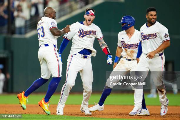 Jonah Heim of the Texas Rangers celebrates with teammates after hitting a walk off one-run single in the tenth inning to win the game between the...