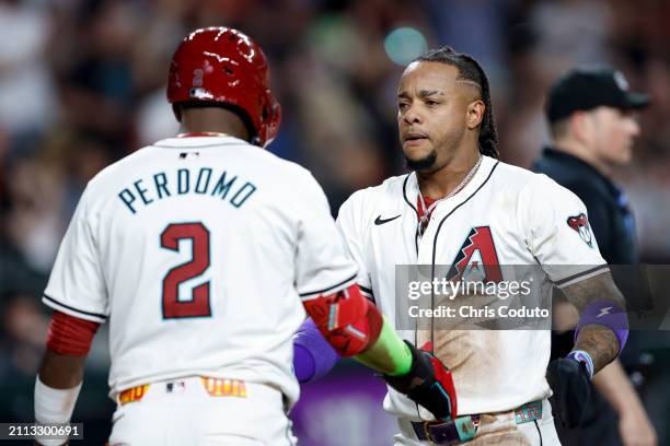 Geraldo Perdomo and Ketel Marte of the Arizona Diamondbacks interact after Marte scores in the third inning of the game between the Colorado Rockies...