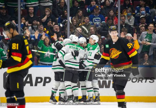 Jason Robertson of the Dallas Stars celebrates his goal with teammates as the Vancouver Canucks skate on dejected during the third period of their...