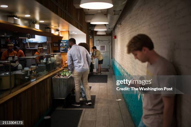 March 12: Dinner customers wait in line for food near the refrigerator door at Chicken and Whiskey, in Washington, DC on Tuesday, March 12, 2024. The...
