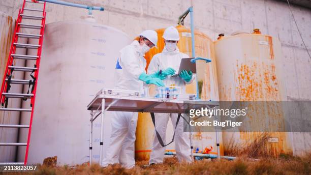 two specialists taking water samples at a sewage treatment plant. - water tower storage tank stock pictures, royalty-free photos & images
