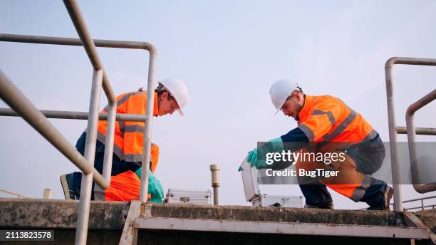 dos especialistas toman muestras de agua en una planta de tratamiento de aguas residuales. - tanque de almacenamiento fotografías e imágenes de stock