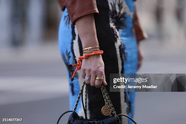 Karin Teigl seen wearing Zara blue / white / black print pattern midi long skirt, Chanel black leather 22 mini bag, Miu Miu orange bracelet, Oura...