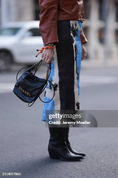 Karin Teigl seen wearing Zara brown leather short jacket, Zara blue / white / black print pattern midi long skirt, Chanel black leather 22 mini bag,...