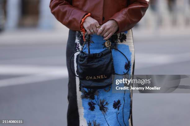 Karin Teigl seen wearing Zara brown leather short jacket, Zara blue / white / black print pattern midi long skirt, Chanel black leather 22 mini bag,...