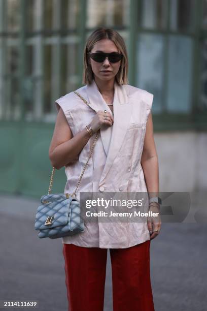 Karin Teigl seen wearing Bottega Veneta black / silver sunglasses, Chanel pearl chain, Zara light pink silk long suit vest, Zara red silk long wide...