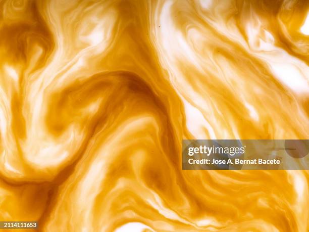 full frame of moving coffee with mixed milk in cup. - kaffee macchiato stock-fotos und bilder