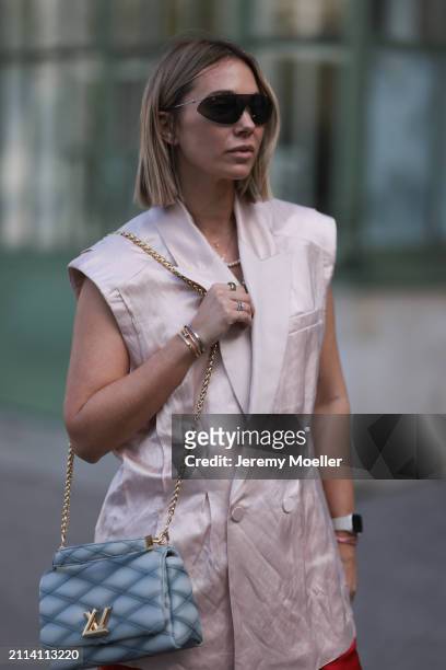 Karin Teigl seen wearing Bottega Veneta black / silver sunglasses, Chanel pearl chain, Zara light pink silk long suit vest, Louis Vuitton Go 14 baby...
