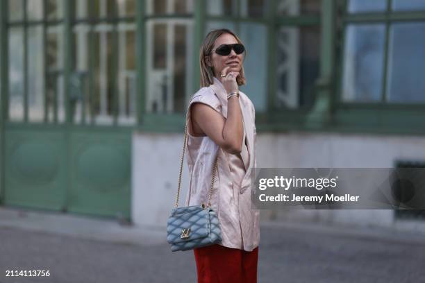 Karin Teigl seen wearing Bottega Veneta black / silver sunglasses, Zara light pink silk long suit vest, Zara red silk long wide leg pants, Louis...