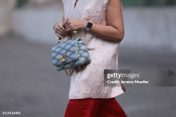 Karin Teigl seen wearing Zara light pink silk long suit vest, Zara red silk long wide leg pants, Louis Vuitton Go 14 baby blue leather bag, Apple...