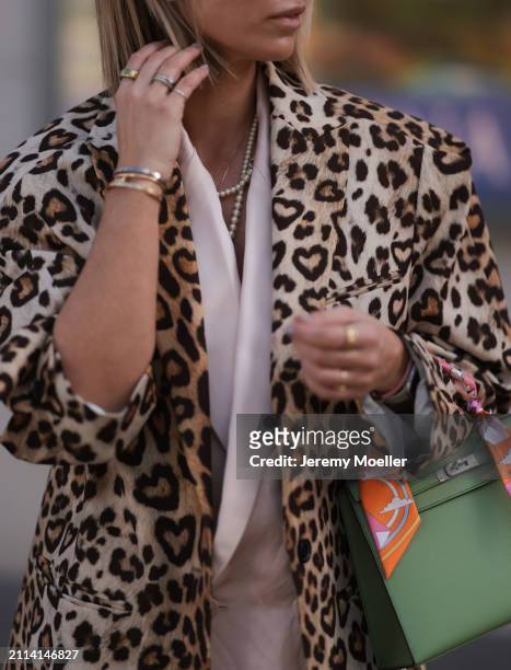 Karin Teigl seen wearing Chanel pearl necklace, Zara light pink silk long suit vest, H&M Studios leopard print pattern long coat, Oura gold smart...