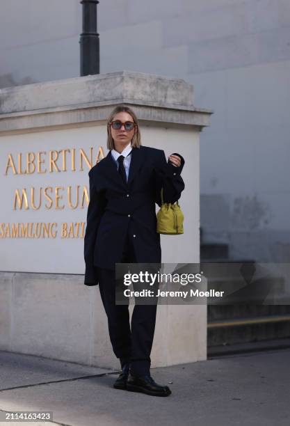 Karin Teigl seen wearing Jacques Marie Mage brown sunglasses with blue lenses, By Aylin Koenig white cotton buttoned shirt, H&M black tie, Prada navy...