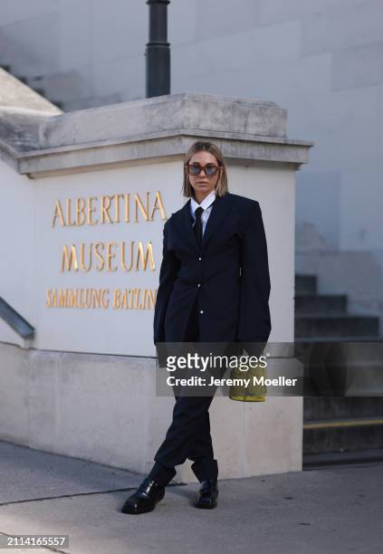 Karin Teigl seen wearing Jacques Marie Mage brown sunglasses with blue lenses, By Aylin Koenig white cotton buttoned shirt, H&M black tie, Prada navy...
