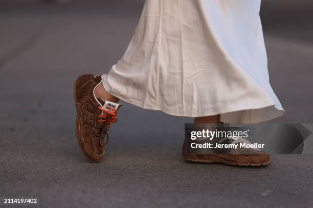 Karin Teigl seen wearing Mango creamy white long silk / satin skirt and Miu Miu x New Balance brown suede leather sneakers, on March 23, 2024 in...
