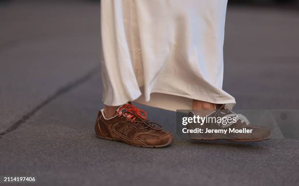 Karin Teigl seen wearing Mango creamy white long silk / satin skirt and Miu Miu x New Balance brown suede leather sneakers, on March 23, 2024 in...