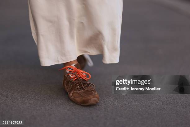 Karin Teigl seen wearing Mango creamy white long silk / satin skirt and Miu Miu x New Balance brown suede leather sneakers, on March 23, 2024 in...