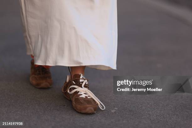 Karin Teigl seen wearing Mango creamy white long silk / satin skirt and Miu Miu x New Balance brown suede leather sneakers, on March 23, 2024 in...