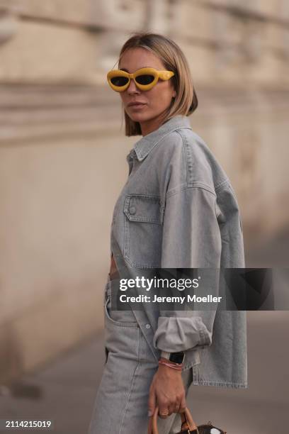 Karin Teigl seen wearing Loewe yellow sunglasses, gold necklaces, Agolde light grey denim buttoned jeans shirt and Apple silver smart watch, on March...