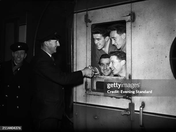 London railway porter shaking hands with West Ham footballers Harry Hooper , Andy Malcolm , Freddie Kearns and Tommy Dixon , February 5th 1954.