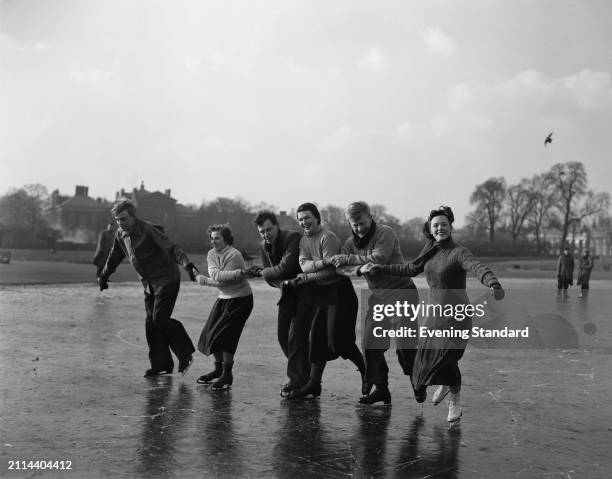 People linking arms and ice-skating on the frozen Round Pond in Kensington Gardens, London, February 7th 1954.