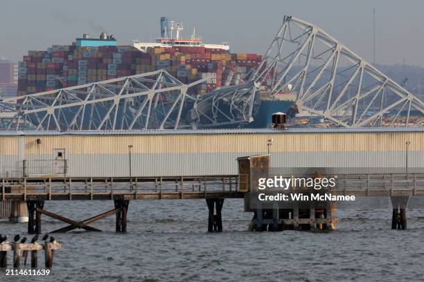 Local residents watch as a cargo ship is shown after running into and collapsing the Francis Scott Key Bridge on March 26, 2024 in Baltimore,...