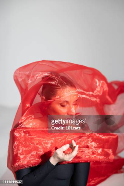portrait of middle-aged female actress behind red tulle - 101cats stock pictures, royalty-free photos & images
