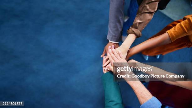 diverse businesspeople standing together with their hands in a pile in an office - teamwork makes the dream work stock pictures, royalty-free photos & images
