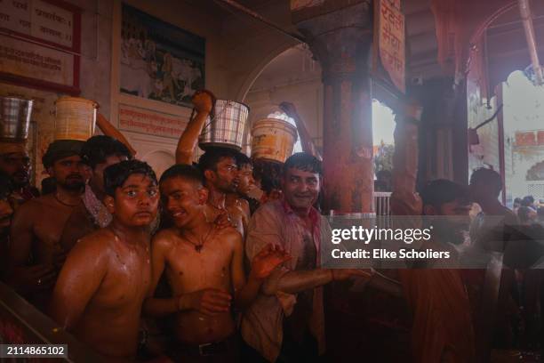 Hindu devotees carry buckets with coloured water to throw on women during the Huranga festival on March 26, 2024 in Mathura, India. The Huranga...