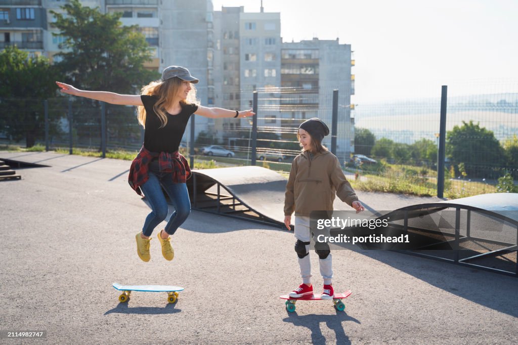 Mother and son having skateboarding training in skateboard park