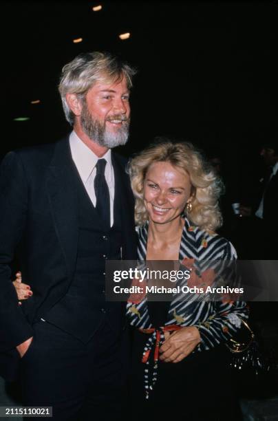 American actor and singer Troy Donahue, wearing a black three-piece suit over a white shirt with a black tie, accompanied by a woman wearing a...