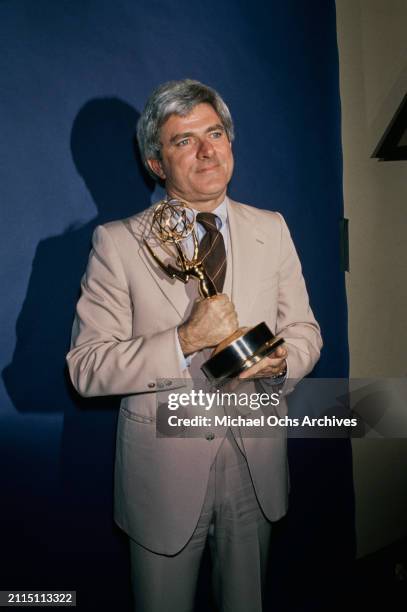 American talk show host Phil Donahue, wearing a beige three-piece suit with a white shirt and a diagonally striped brown tie, in the 6th Daytime Emmy...