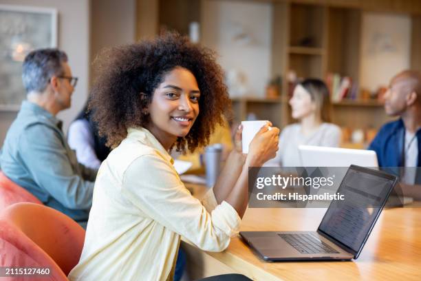 businesswoman smiling in a business meeting while drinking coffee - hispanolistic stock pictures, royalty-free photos & images