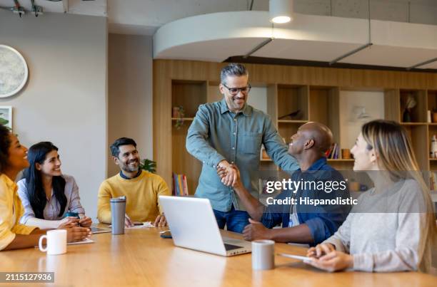 businessman getting a promotion and handshaking with his boss - hispanolistic stock pictures, royalty-free photos & images