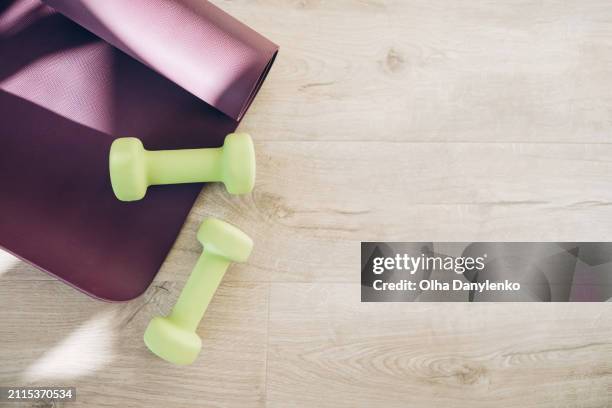 flat lay of yoga, sports and fitness equipment with green dumbbells and yoga mat. fitness, wellness and home work out concept - colchoneta de ejercicio fotografías e imágenes de stock