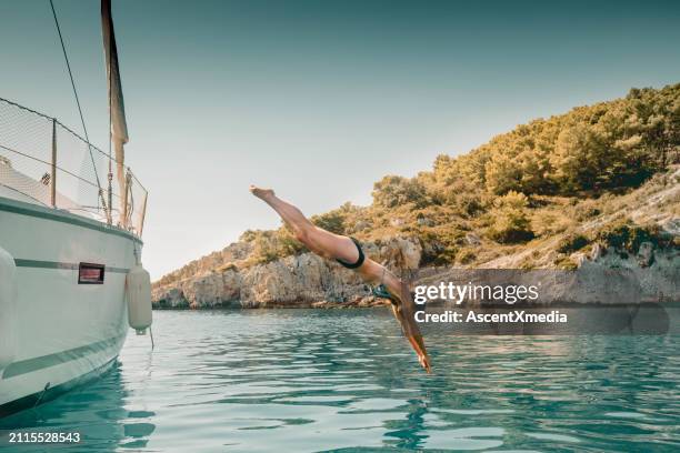 une jeune femme plonge d’un voilier - yachting photos et images de collection