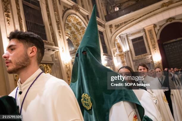 Penitents from the Gran Poder brotherhood are seen inside the Church of San Isidro while conducting a mass on Holy Thursday, as the procession was...