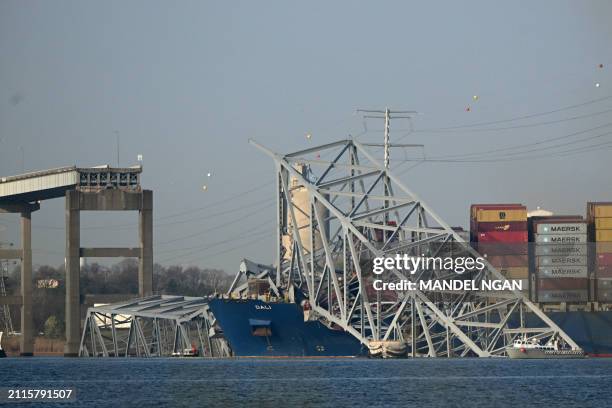 The collapsed Francis Scott Key Bridge lies on top of the container ship Dali in Baltimore, Maryland, on March 29 as clean-up work begins.. Cranes...