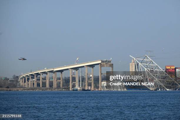 The collapsed Francis Scott Key Bridge lies on top of the container ship Dali in Baltimore, Maryland, on March 29 as clean-up work begins.. Cranes...