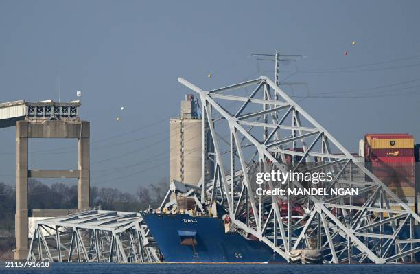 The collapsed Francis Scott Key Bridge lies on top of the container ship Dali in Baltimore, Maryland, on March 29 as clean-up work begins.. Cranes...