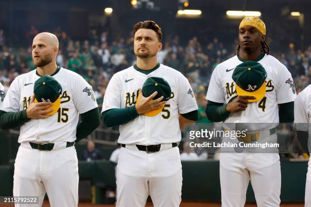 Seth Brown, J.D. Davis and Lawrence Butler of the Oakland Athletics look on during the singing of the national anthem prior to the game between the...
