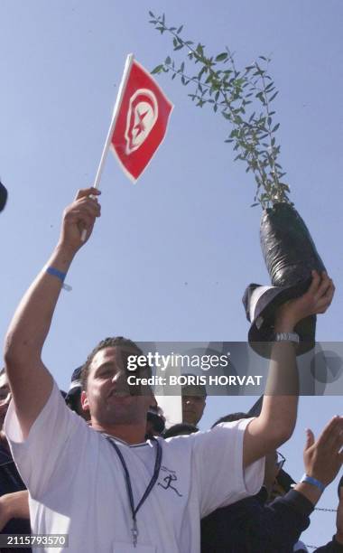 Un jeune Tunisien brandit le drapeau national et un jeune olivier, le 13 mai à Arles, lors de la clôture du rassemblement de jeunes venus d'une...