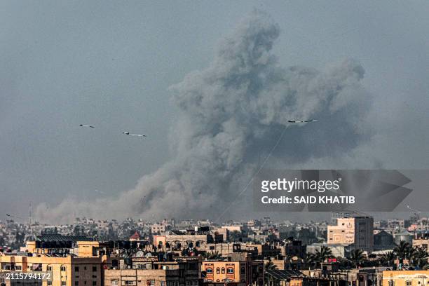 Kites fly in Rafah as a smoke plume erupts during Israeli bombardment on Khan Yunis in the southern Gaza Strip on March 29 amid ongoing battles...
