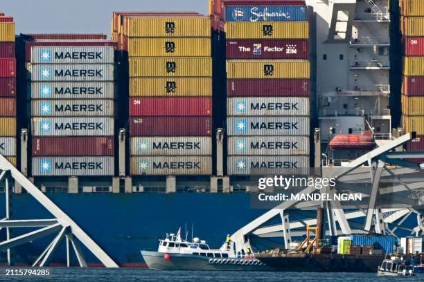 The collapsed Francis Scott Key Bridge lies on top of the container ship Dali in Baltimore, Maryland, on March 29 as clean-up work begins.. Cranes...