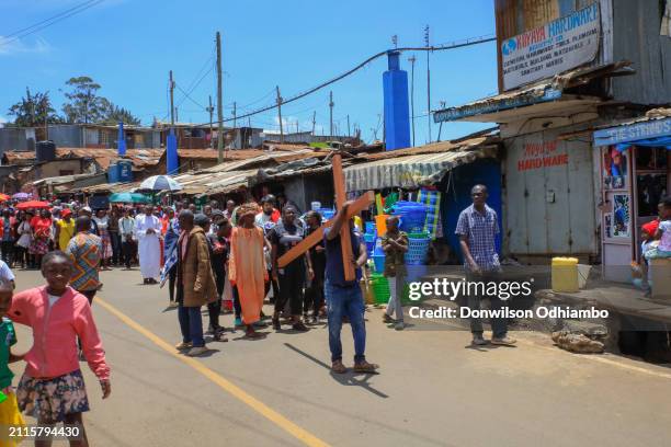 Man carries a cross during Good Friday procession in Kibera Slum on March 29, 2024 in Nairobi, Kenya.