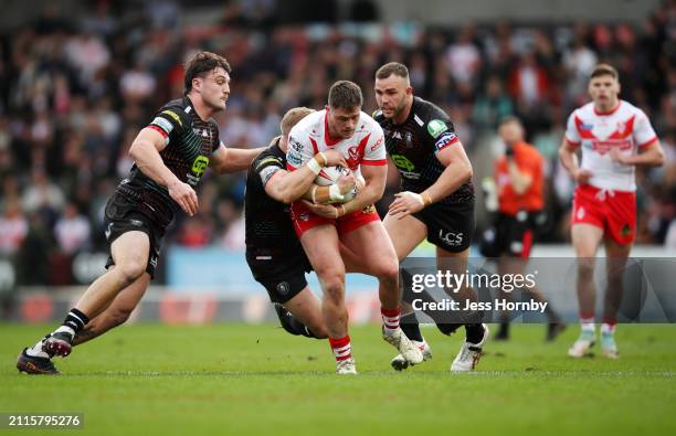 Morgan Knowles of St.Helens is tackled by Liam Byrne and Kaide Ellis of Wigan Warriors during the Betfred Super League match between St Helens and...
