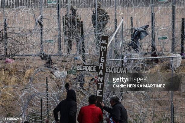 Migrants place a cross in front of a wire fence as they take part in the "Migrant's Via Crucis," a simulation of Jesus Christ's Via Crucis, held at...