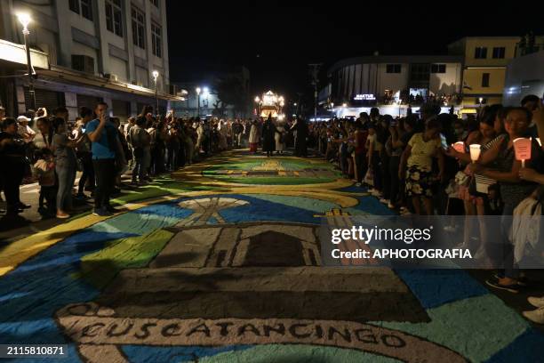 Catholic devotees carry the figure of Jesus Christ in an urn walking on carpets as part of the Holy Burial Procession during the Via Crucis and...