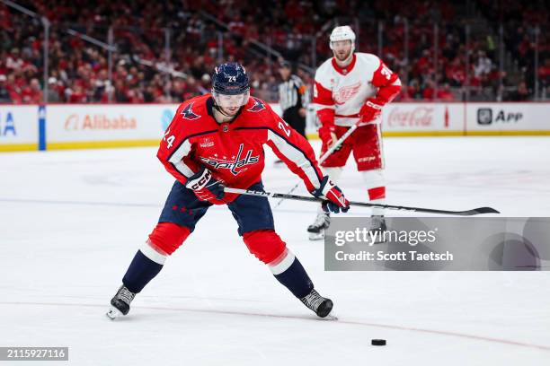 Connor McMichael of the Washington Capitals shoots the puck in front of Christian Fischer of the Detroit Red Wings during the second period of the...
