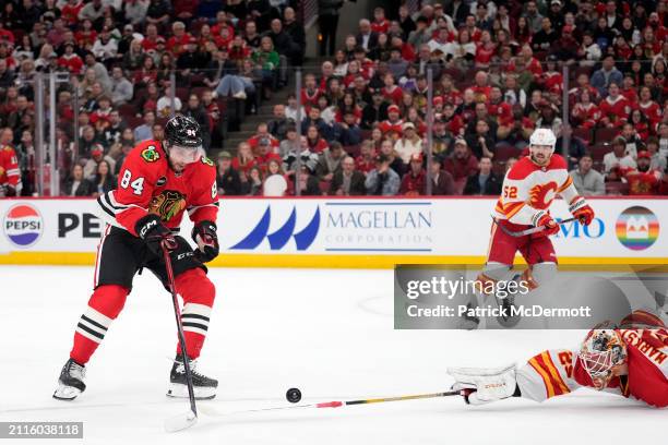 Landon Slaggert of the Chicago Blackhawks skates with the puck past Jacob Markstrom of the Calgary Flames during the second period at the United...