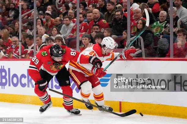 Andreas Athanasiou of the Chicago Blackhawks and Nikita Okhotiuk of the Calgary Flames battle for the puck during the second period at the United...